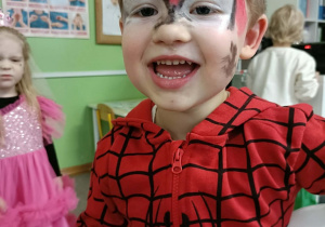 Chłopiec przebrany za Spidermana uśmiecha się do zdjęcia.