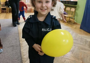 Chłopiec przebrany za policjanta trzyma w dłoni żółty balonik.