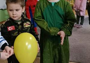 Dwóch chłopców pozuje do zdjęcia. Jeden z chłopców trzyma w dłoni żółty balonik.