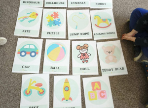 Na szarym dywanie leżą kolorowe karty.