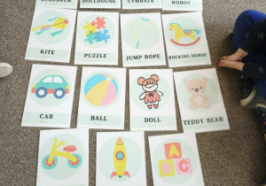 Na szarym dywanie leżą kolorowe karty.