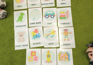 Na zielonym dywanie leżą kolorowe karty.