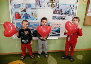 Trzech chłopców pozuje do zdjęcia z balonami w dłoniach.