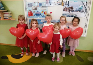 Sześć dziewczynek chłopców pozuje do zdjęcia z balonami w dłoniach.