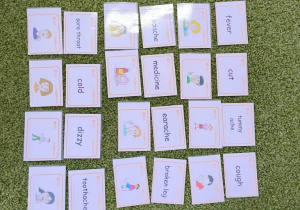 Na zielonym dywanie leżą kolorowe karty.