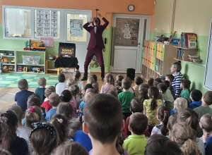 Dzieci siedzą na dywanie i oglądają pokaz.