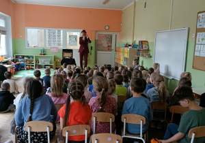 Dzieci siedzą na dywanie i oglądają pokaz.