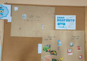 Dwa plakaty wiszą na tablicy korkowej. Pomiędzy nimi wisi napis "Dzień Dentysty".