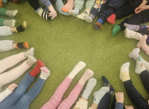 Na zielonym dywanie widać kolorowe skarpetki dzieci.