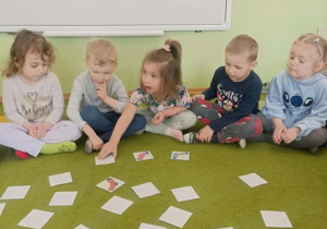 Dziewczynka w ciemnych włosach otwiera karty.