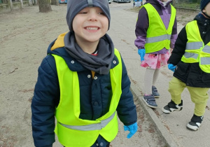 Chłopiec w zielonej kamizelce uśmiecha się do zdjęcia.