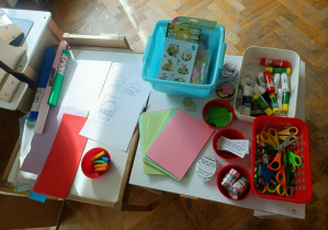 Na stolikach siedzą przygotowane artykuły plastyczne.