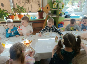 Dzieci siedzą przy stole nakrytym białym obrusem.