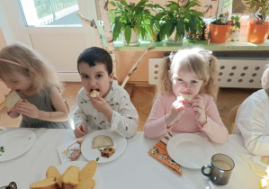 Dzieci jedzą jajko i chleb z masłem.