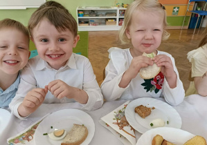 Trójka dzieci uśmiecha się do zdjęcia.