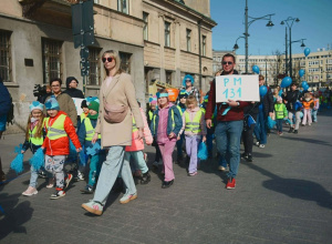 Dzieci maszerują w niebieskich opaskach na głowach.