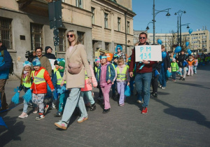 Dzieci maszerują w niebieskich opaskach na głowach.
