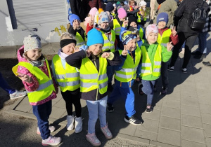 Grupa dzieci stoi na chodniku.