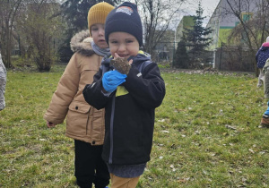 Chłopiec w czarnej kurtce trzyma w dłoni liście.