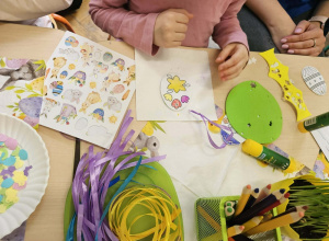 Na stoliku leżą materiały plastyczne oraz ozdabiane pisanki.
