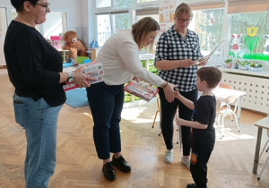 Pani Dyrektor wręcza chłopcu nagrodę. Po bokach stoją dwie Panie prowadzące.
