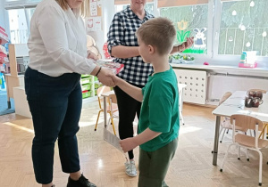 Pani Dyrektor wręcza chłopcu nagrodę.