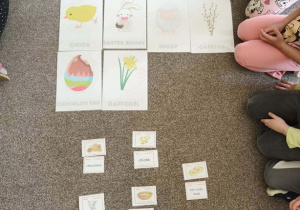 Obrazkowe plansze z symbolami świątecznymi leżą na zielonym dywanie.