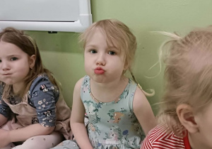 Dziewczynka w sukience robi dziubek z ust.