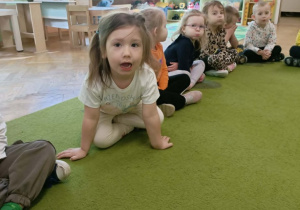 Dzieci siedzą na dywanie i nadymają buzie.