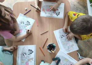 Dzieci kolorują kolorowanki ze zwierzętami.