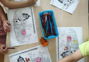 Dzieci kolorują kolorowanki ze zwierzętami.