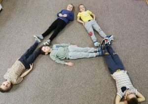 kształt literki A - dzieci leżące na dywanie