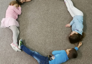 kształt literki O - dzieci leżące na dywanie