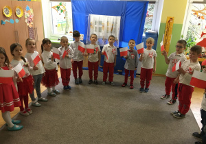 dzieci w biało-czerwonych strojach z flagami Polski i kotylionami