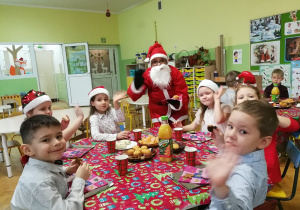 dzieci jedzą słodki poczęstunek z Mikołajem
