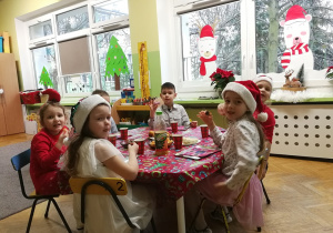 dzieci jedzą słodki poczęstunek, dekoracje zimowe w oknach