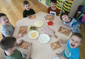 dzieci tworzą własną pizzę z różnych składników