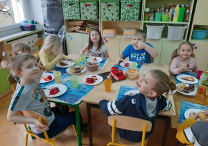 zadowolone dzieci jedzą tort i babeczki