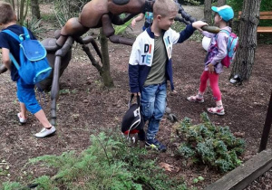 Grupka dzieci ogląda i dotyka wielką brązowa mrówkę