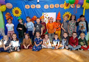 Dzieci w strojach jesiennych pozują do zdjęcia na tle dekoracji