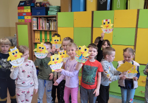 Grupa dzieci pozuje do zdjęcia z pracami o tematyce wielkanocnej w tle kolorowe szafki