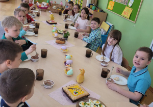 Dzieci siedzą przy stole przy wielkanocnym posiłku