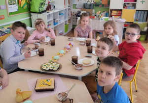 Dzieci siedzą przy stole przy wielkanocnym posiłku