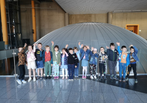 Grupa dzieci pozuje do zdjecia przed kopuła planetarium