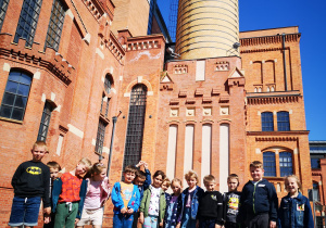 Grupa dzieci pozuje do zdjęcia przed budynkiem EC1