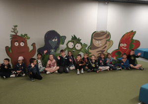 Grupa dzieci pozuje do zdjecia na tle kolorowej grafiki