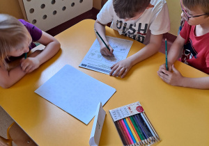 Dzieci przy stoliku wykonują zadanie matematyczne