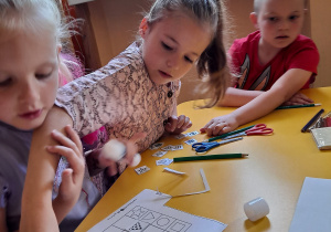 Dzieci przy stoliku wykonują zadanie matematyczne