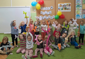 Dzieci pozują do zdjęcia z figurkami z balonów w tle napis Dzień Przedskzolaka