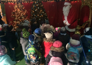 Mikołaj rozmawia z dziećmi, w tle choinka świąteczna